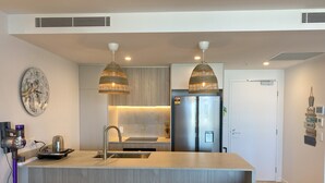 A modern kitchen with a central island, stainless steel appliances, and pendant lighting.