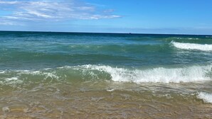 A beach with clear blue water and waves.