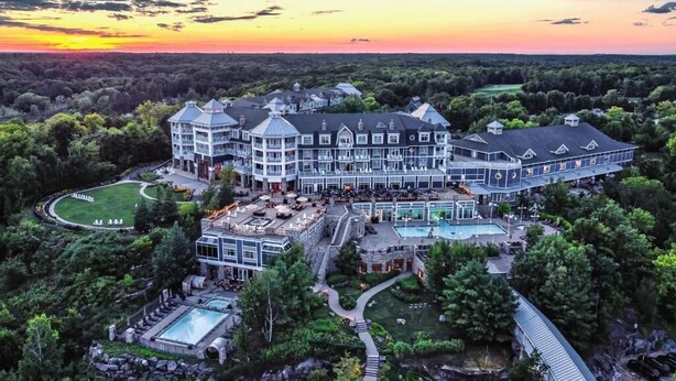 A large, multi-story hotel with a central courtyard, outdoor pool, and a scenic sunset view.