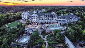 A large, multi-story hotel with a central courtyard, outdoor pool, and a scenic sunset view.