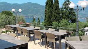 An outdoor terrace with tables and chairs, overlooking a lake and mountains. - Vacation home Eden by Interhome (San Felice del Benaco)
