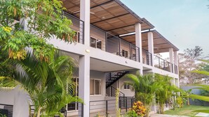 A modern two-story building with a balcony, surrounded by tropical plants and a small pool area. - Akira  (Tamarindo)