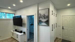 Een moderne keuken met een ingebouwde televisie, witte kasten en een houten vloer.