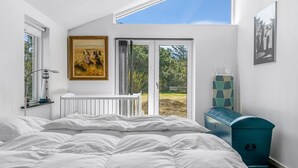Une chambre avec un grand lit, un tableau, un radiateur, une fenêtre et une vue sur l’extérieur.