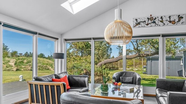 Un salon moderne avec une table en verre, des canapés en cuir et une grande fenêtre donnant sur un jardin.