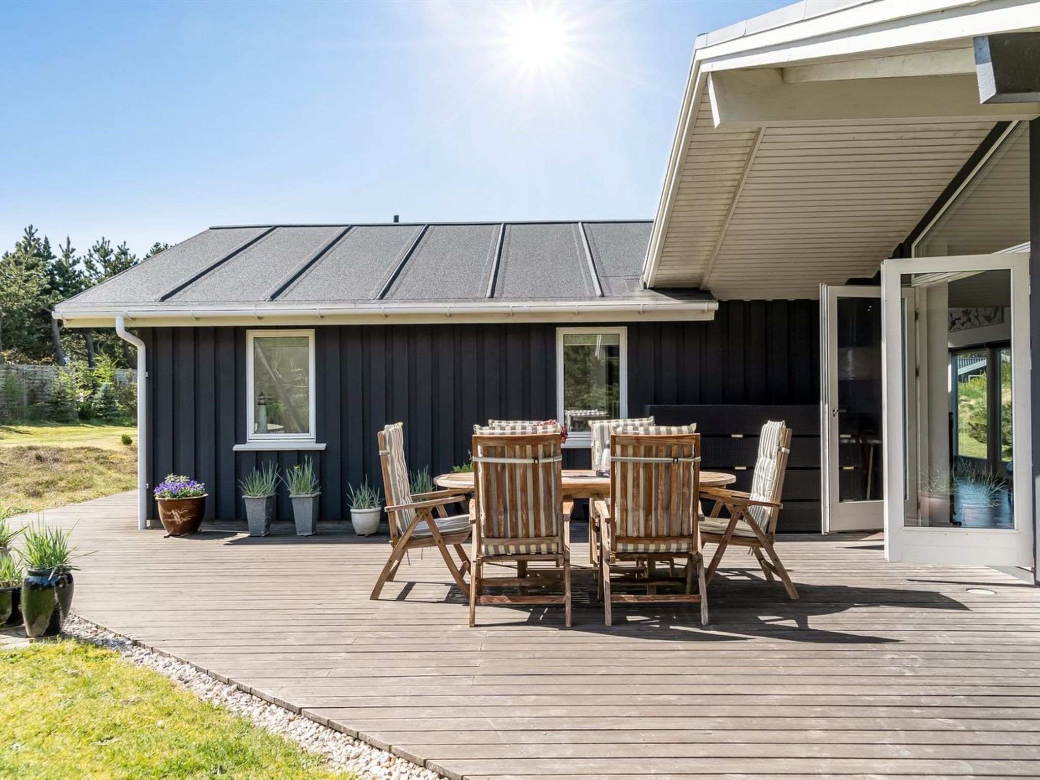 Et moderne hus med terrasse, udendørs møbler og et stort vindue.