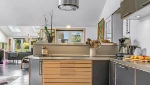 Une cuisine moderne dotée d’un îlot central, d’appareils électroménagers intégrés et d’une grande fenêtre qui laisse entrer la lumière naturelle.