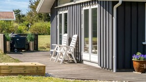 Une maison moderne dotée d’un patio couvert comprenant un espace salon extérieur et un barbecue.