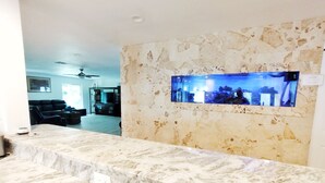 Ein Empfangsbereich mit einer Marmor-Apotheke, einem großen Aquarium und einer Sitzecke im Hintergrund.