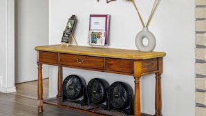 Un tavolo consolle in legno con uno specchio, un vaso con pampas secchi e un orologio appeso al muro.