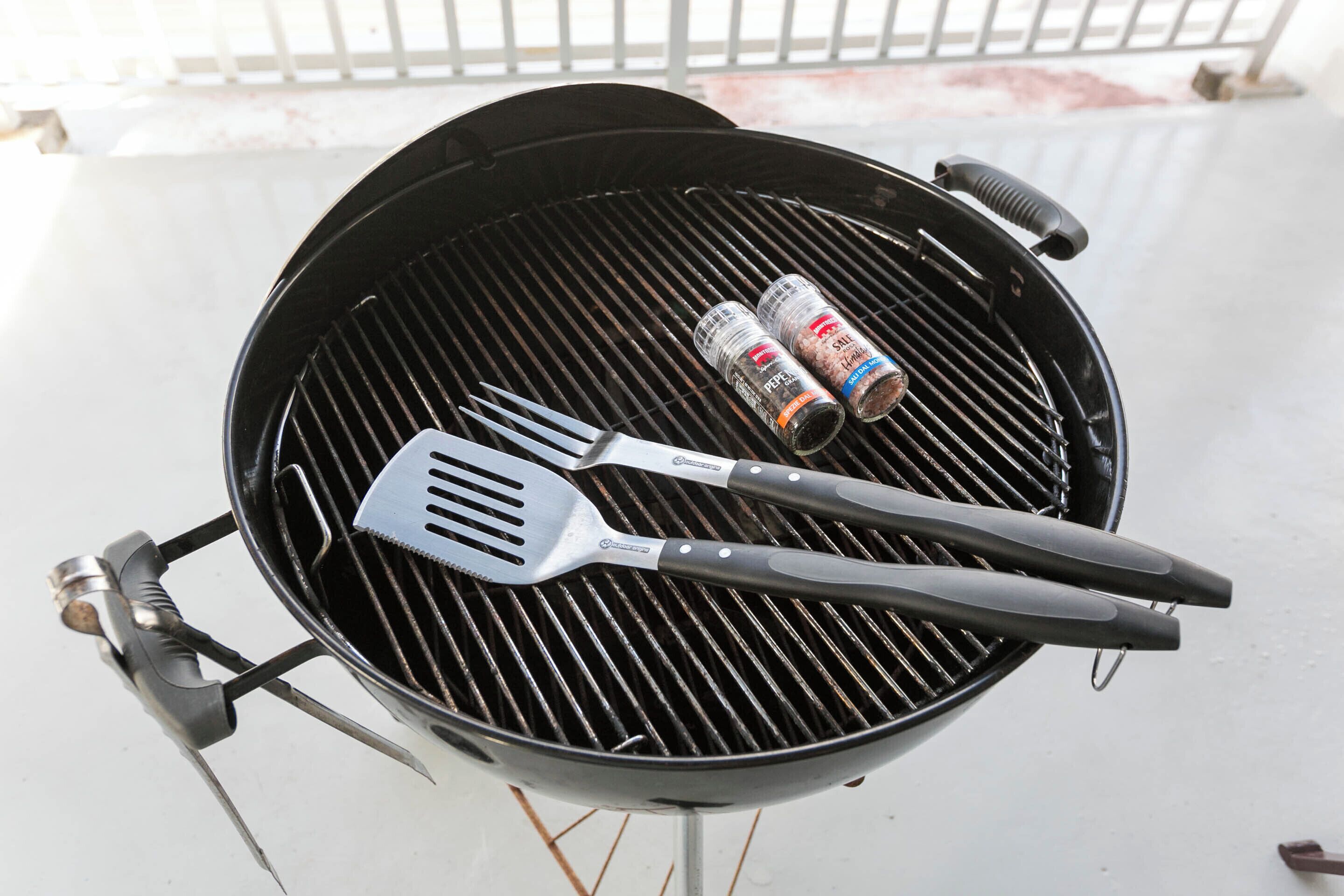A grill with two barbecue utensils and a can of barbecue sauce.