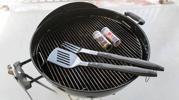 A grill with two barbecue utensils and a can of barbecue sauce.