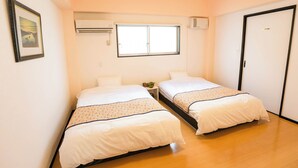 A hotel room with two beds, a window, an air conditioning unit, and a door. - Public Inn Okinawa (Chatan)