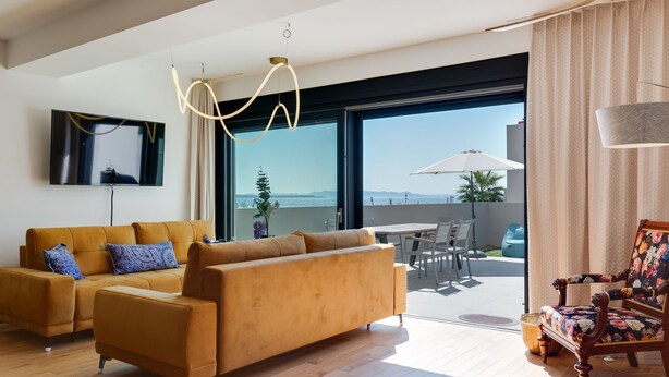 A modern living room with a sofa, a TV, and a balcony with a table and chairs. - Watergate by Interhome (Privlaka)