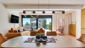 A modern living room with a large oval table, comfortable seating, a flat-screen TV, and a view of the outdoors. - Watergate by Interhome (Privlaka)