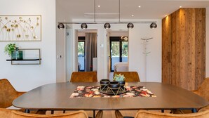 A modern dining area with a large oval table, six chairs, and a central floral table runner. - Watergate by Interhome (Privlaka)