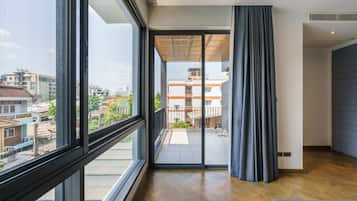 A modern interior with large windows, a balcony, and a view of the cityscape.