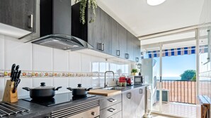 Une cuisine moderne équipée d’une cuisinière, de casseroles, d’un évier et offrant une vue sur l’extérieur.
