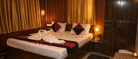 Habitación de hotel con una cama grande, cabecero de madera y cortinas.