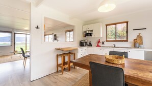 A modern kitchen with white cabinets, a wooden dining table, and a view of the outdoors. - Askew with a View (Dover)