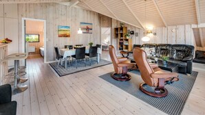 A spacious loft with high ceilings, wooden walls, a dining area, and a cozy seating area with leather chairs and a sofa. - "Sarah" by Interhome (Ansager)