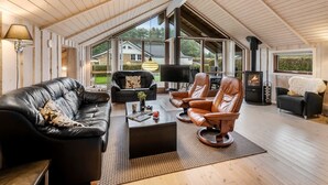 A spacious loft with a high ceiling, large windows, a fireplace, leather sofas, and a dining area. - "Sarah" by Interhome (Ansager)