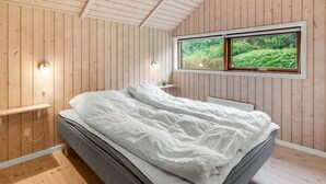 A bedroom with a bed, wooden walls, a window with a view of greenery, and a ceiling light. - "Sarah" by Interhome (Ansager)