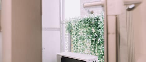 A room with a white air conditioning unit, a white door, and a green leafy wall.
