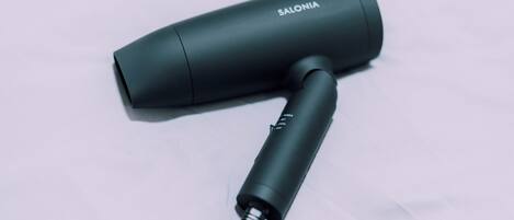Un objeto cilíndrico negro con el texto "SALONIA" sobre una superficie blanca.