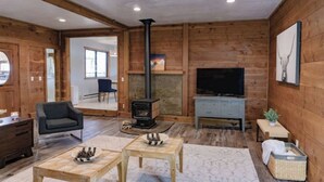 Un salon chaleureux avec une cheminée, un téléviseur et des meubles en bois.