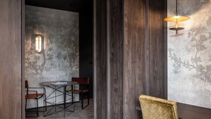 Un comedor moderno con una mesa redonda y dos sillas, una pared con textura y una lámpara colgante.