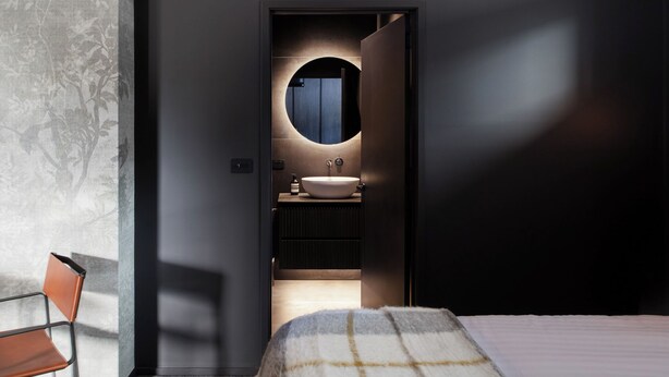 Un baño moderno con un espejo redondo, un lavabo y un perchero para toallas.