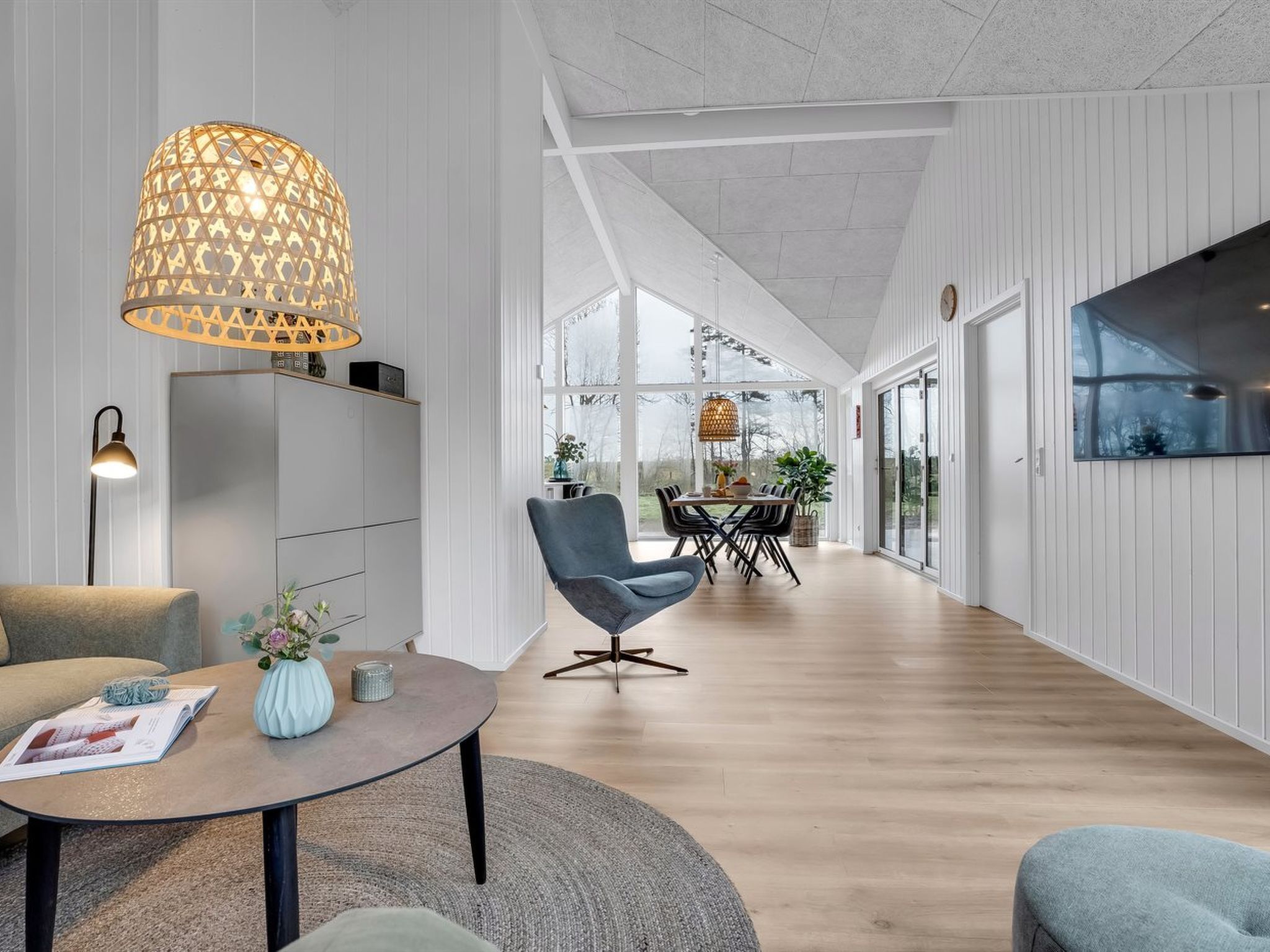 Un intérieur moderne comprenant un coin repas, un canapé, une table basse et une grande fenêtre.