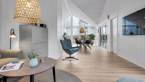 A modern interior with a dining area, a sofa, a coffee table, and a large window.