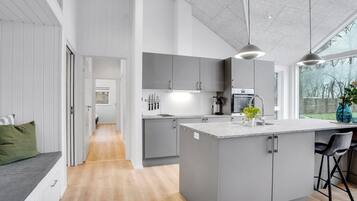 Une cuisine moderne avec des meubles gris, un îlot central et une grande fenêtre.