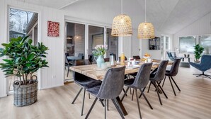 A modern dining area with a wooden table, grey upholstered chairs, and two hanging pendant lights.