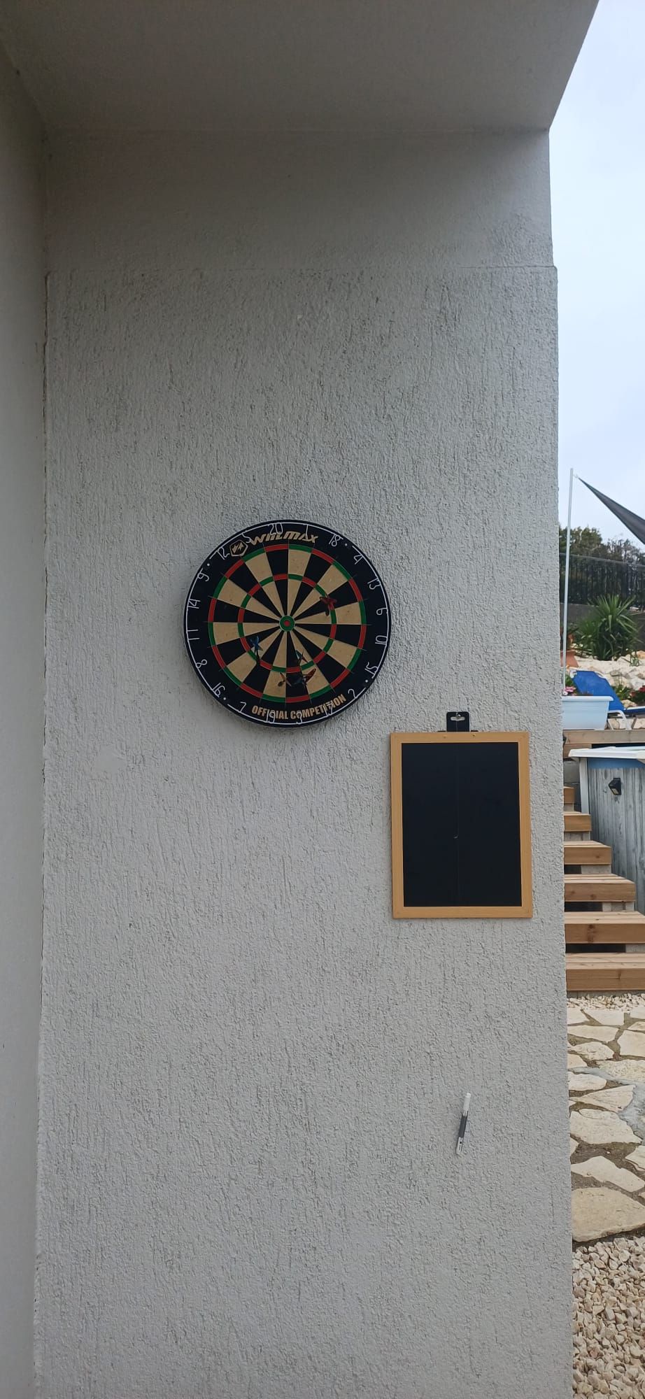 Um alvo de dardos fixado na parede, com um quadro negro abaixo.