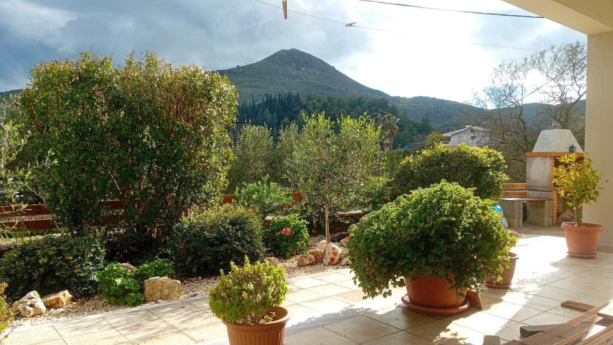A patio with potted plants, a barbecue area, and a mountain view.