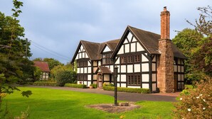 A traditional Tudor-style building with multiple gabled roofs and a prominent stone chimney.
