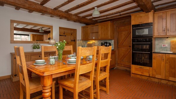 Un comedor con una mesa de madera dispuesta para cuatro personas, rodeado de sillas de madera.