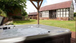 Un jacuzzi en un jardín con un edificio tradicional al fondo.