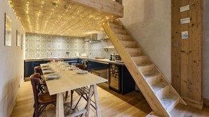 A kitchen with a wooden staircase, a dining table set with plates and glasses, and a patterned backsplash. - Loft Bellevue Remonté | Centre | Piscine | Parking (Les Houches)