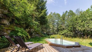 A wooden deck with a hot tub, lounge chairs, and a forest backdrop. - Loft Bellevue Remonté | Centre | Piscine | Parking (Les Houches)