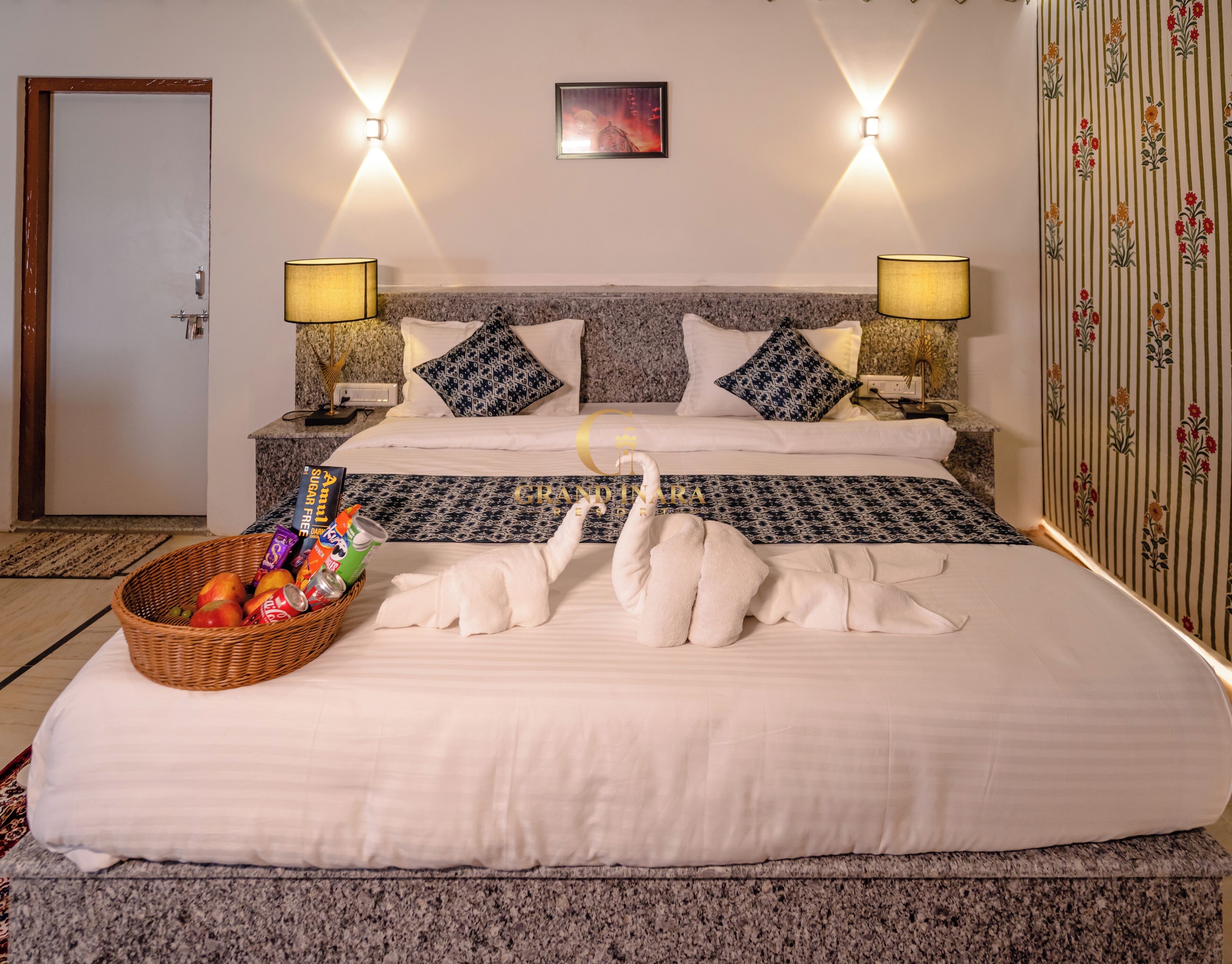 A hotel room with a large bed, two bedside lamps, a wall-mounted picture, and a decorative wall panel.