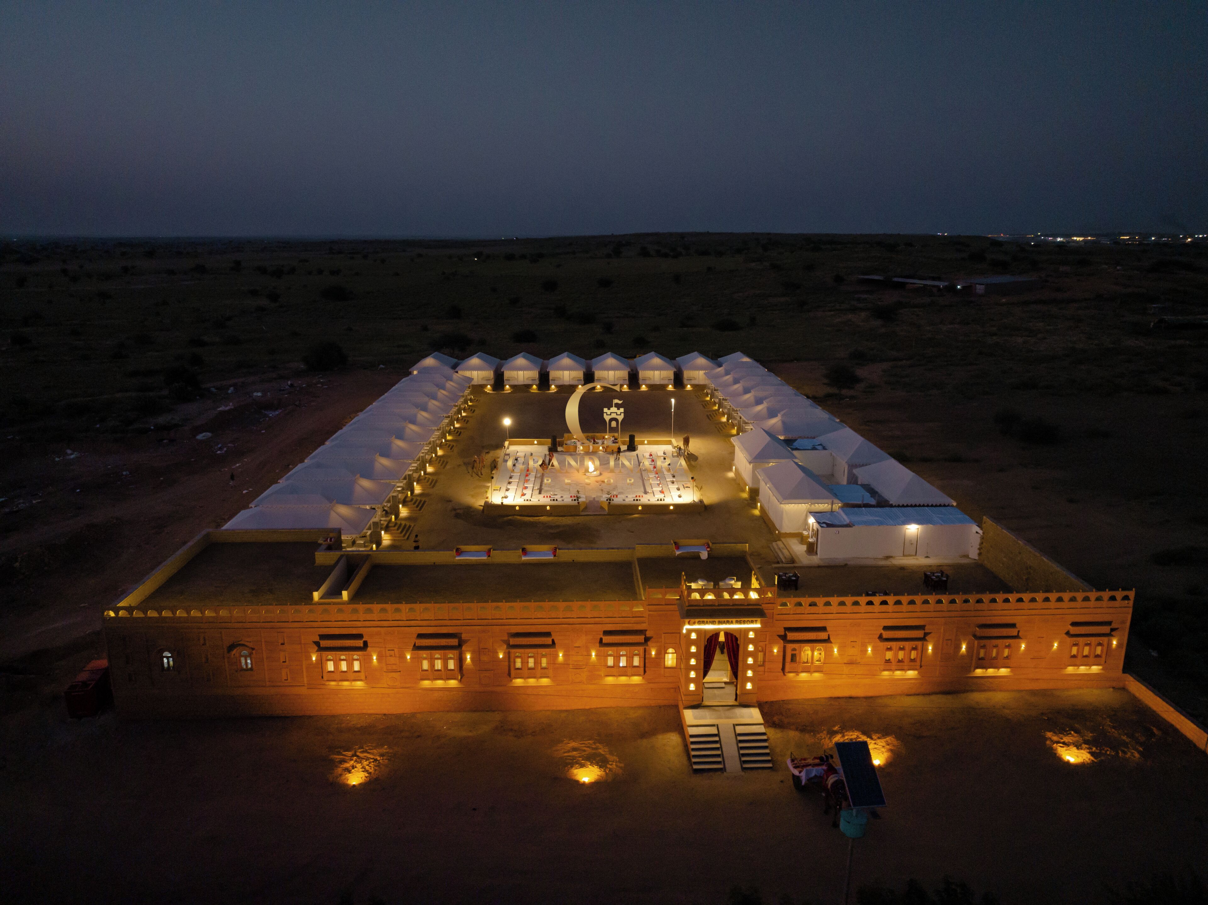 A large, well-lit hotel with multiple tents and a central building, surrounded by a desert landscape.