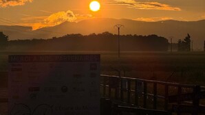 A sunset with the sun low on the horizon, clouds in the sky, and a sign in the foreground. - Gite in the heart of nature 15 minutes from Colmar  (Widensolen)