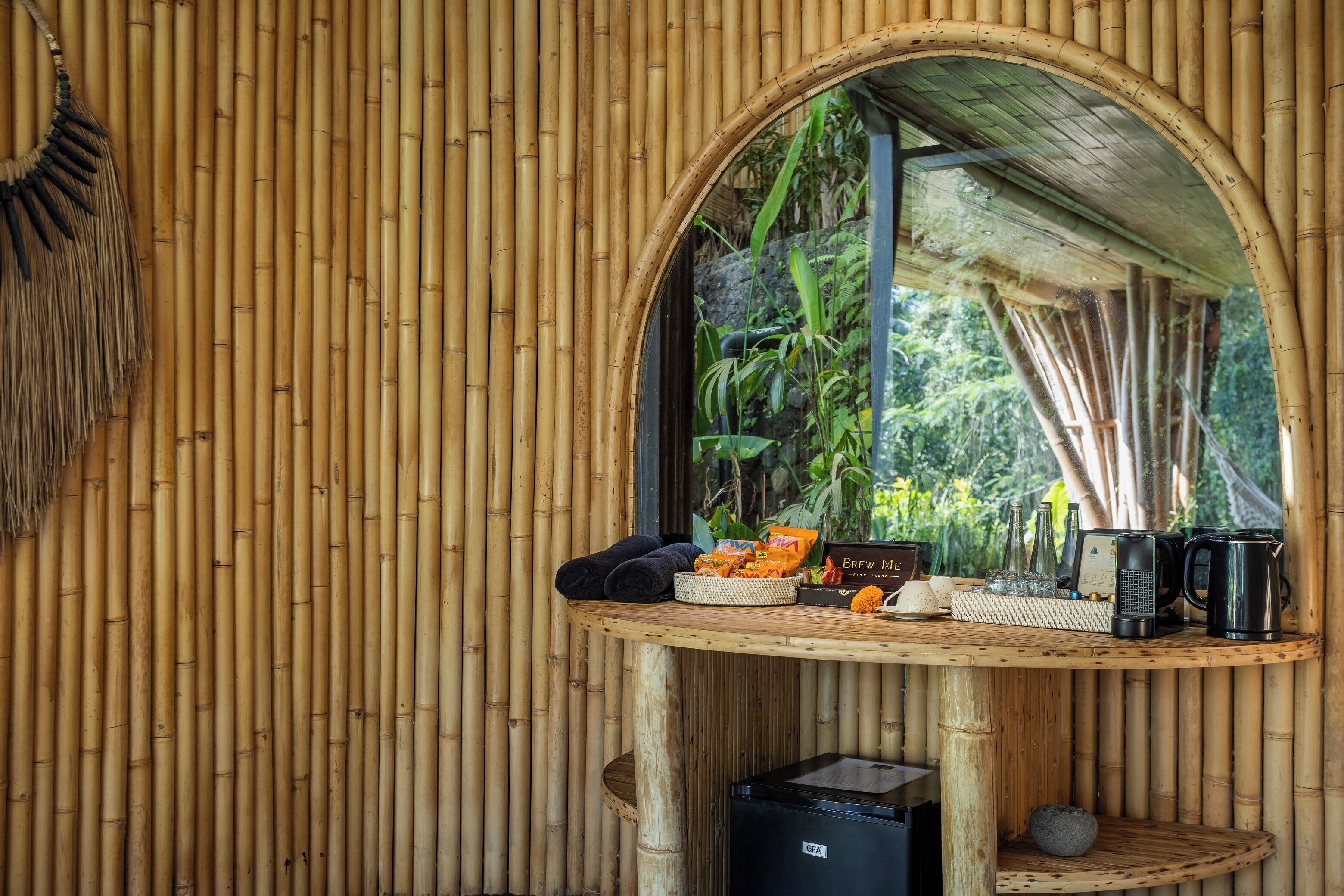A bamboo-framed room with a table holding towels, a coffee maker, and a kettle.