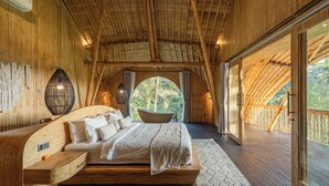 Un dormitorio de madera espacioso con una cama grande, una bañera integrada y vistas al exterior.