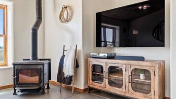 Una habitación con estufa de leña, un mueble de madera con puertas de cristal y un espejo grande en la pared.