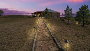 Un camí de pedra que condueix a una casa amb un porxo cobert i il·luminació exterior.